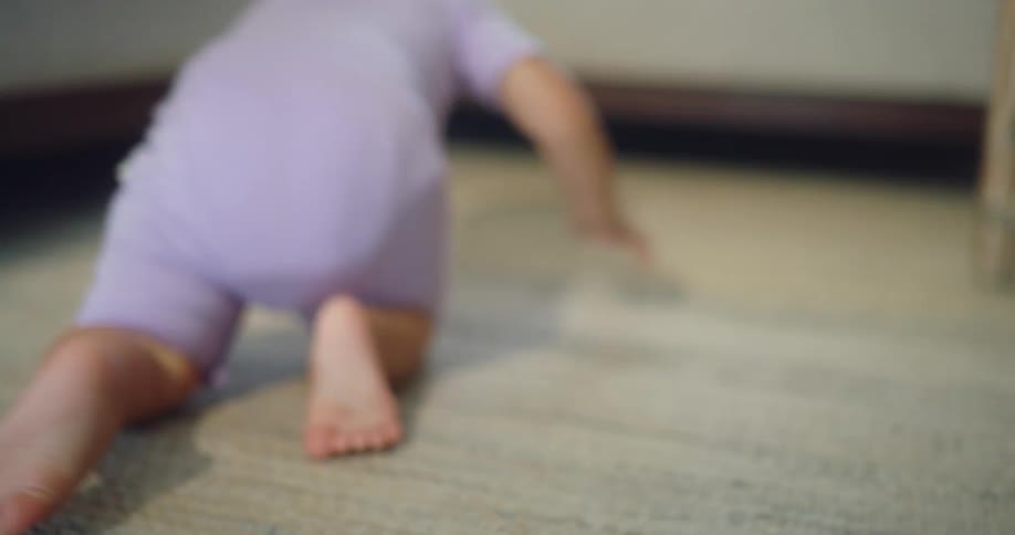 Baby crawling on carpeted flooring towards the couch