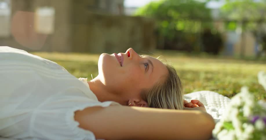 Woman lying on the grass looks at the sky with a smile