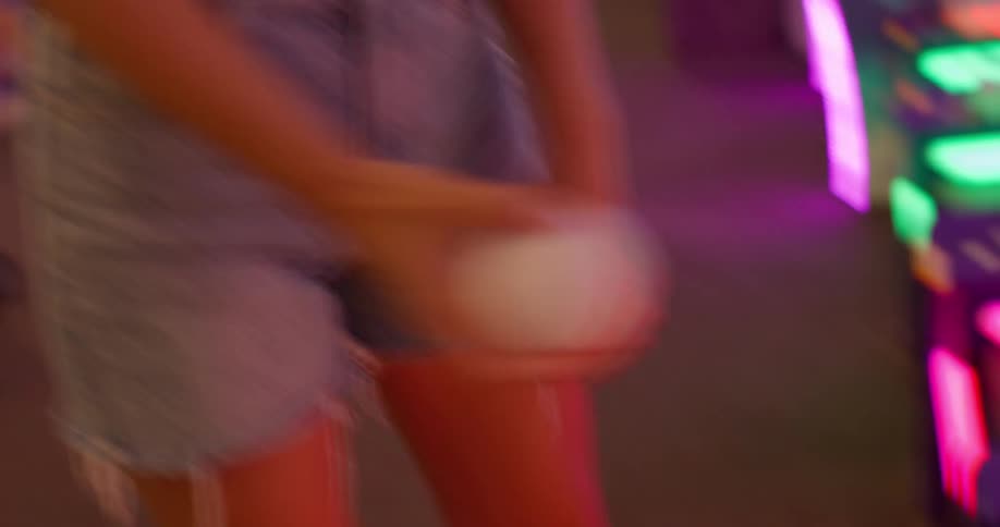 A smiling blonde woman is playing an arcade game she throws a white ball and laughs in delight as she plays