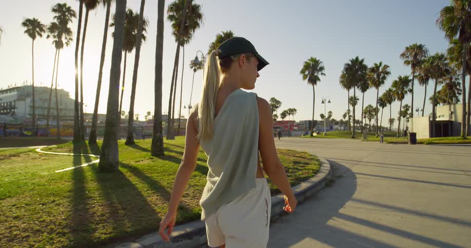 Blonde woman smiles while walking along the road near a shopping area on a sunny summer day