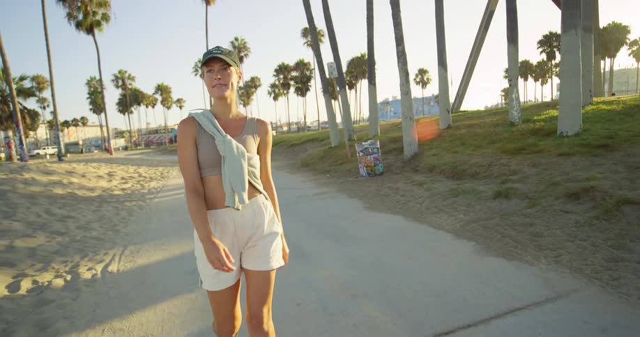 The woman is walking on the sidewalk by the beach