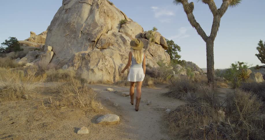 The woman is hiking on the trail in the desert