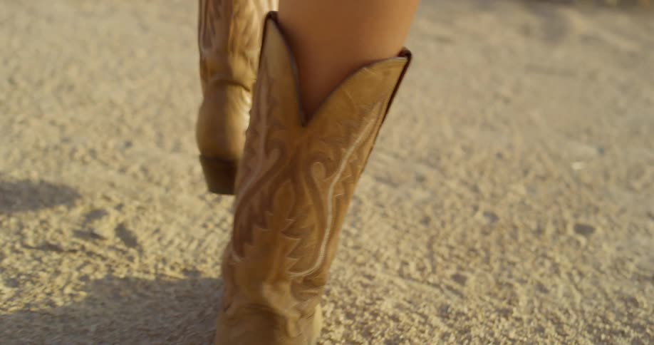 A woman wearing boots walking in the wild under the sun