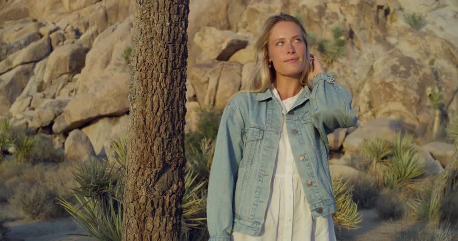Woman in a denim jacket in a rocky arid landscape at sunset