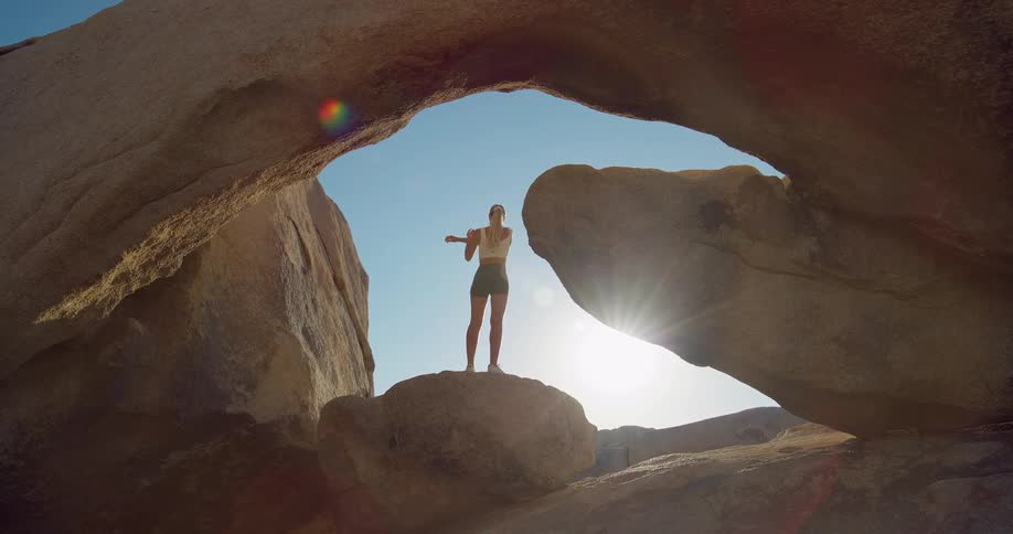 The woman stretches on top of the large rocks