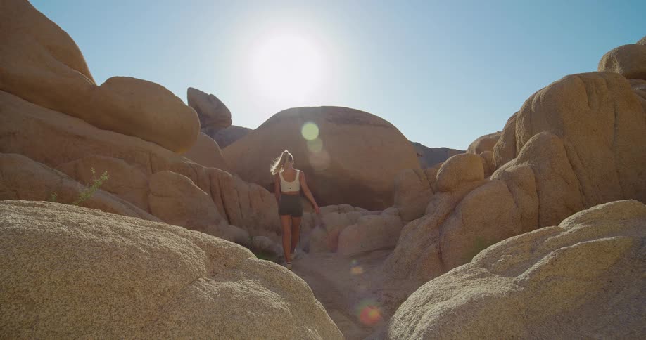 Female hiking in a canyon through boulders turns and smiles