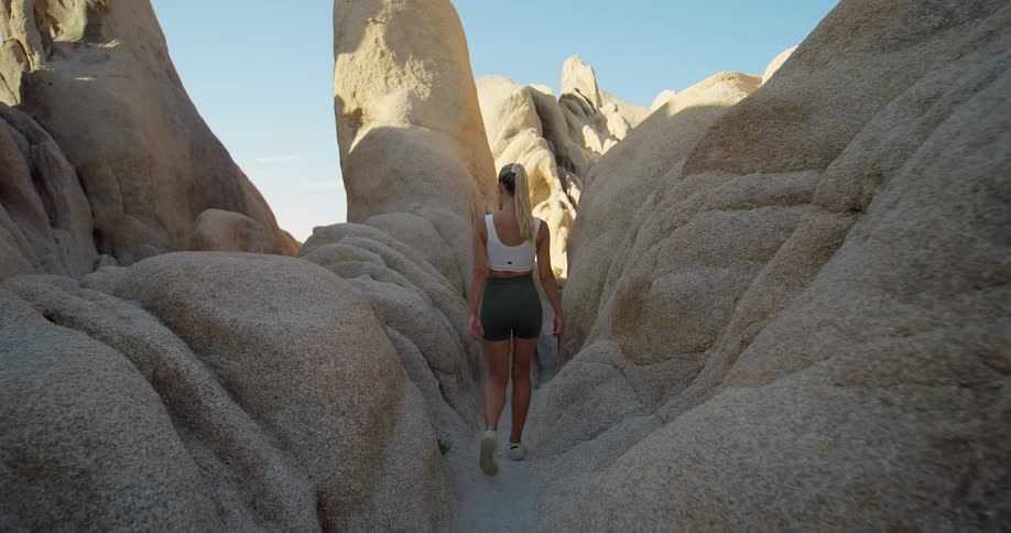 Back of a woman hiking on a narrow path through the canyon