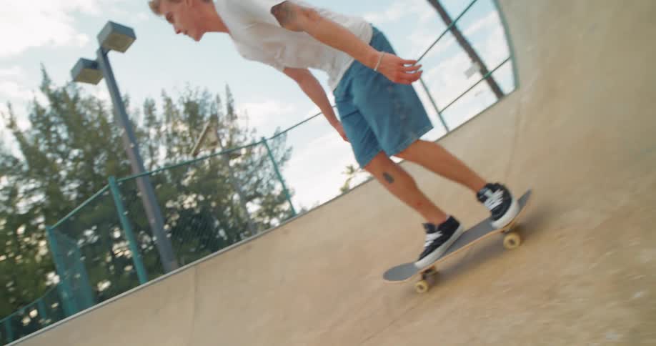 A young person rides a skateboard up a ramp at a skatepark