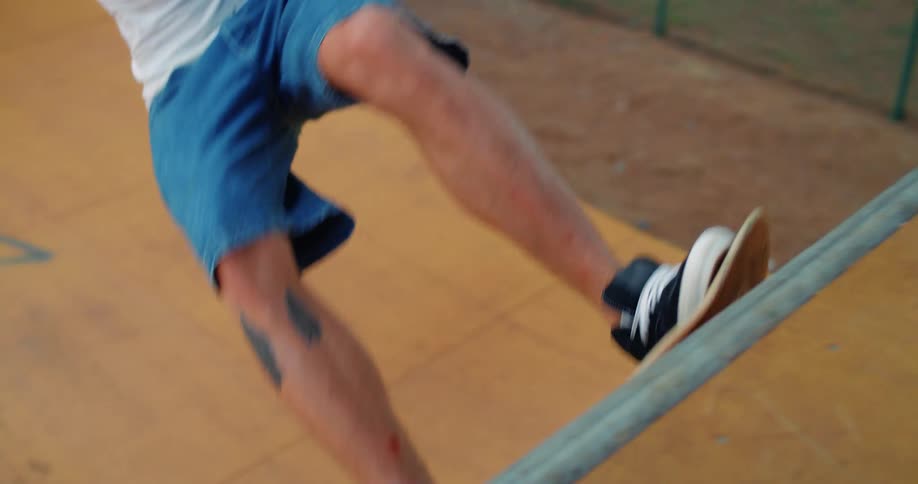 Male skateboarder rides his board up and down the wall of the bowl at a skate park