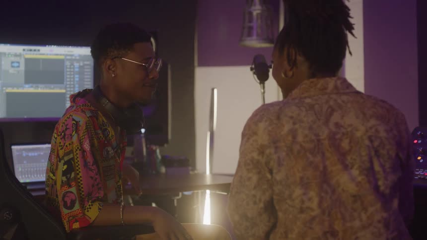 A man and woman listen to music in the studio