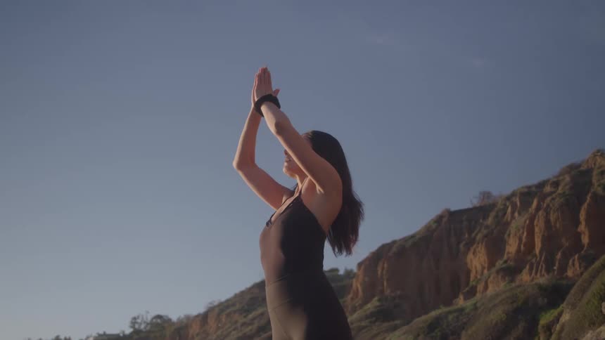 Woman practices yoga outdoors in front of rocky formations
