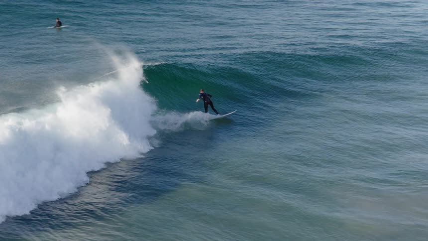A surfer rides down the face of a large ocean wave