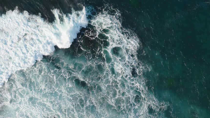 Aerial view of ocean waves breaking and foaming
