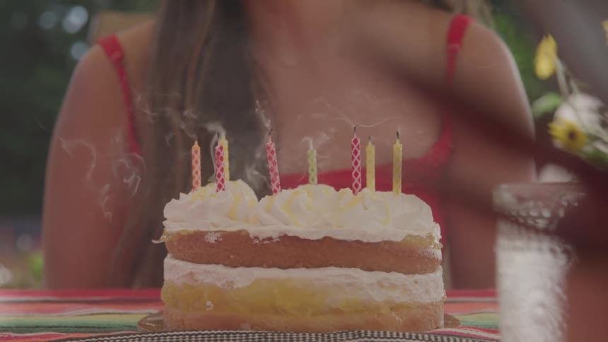Girl claps after blowing the cake candles while sitting outdoor
