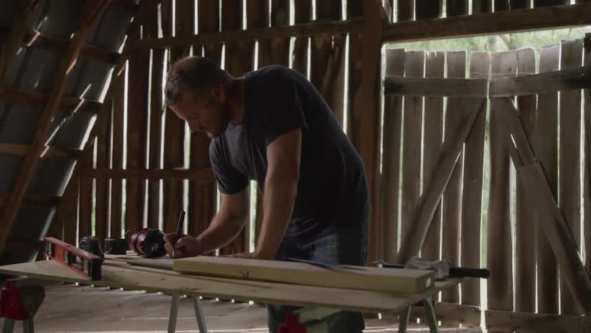 The carpenter is writing something down on the workbench
