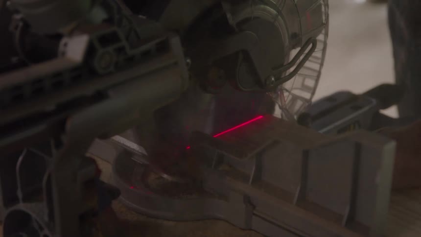 A worm drive dualbevel sliding miter saw cutting through metal indoors at a construction site