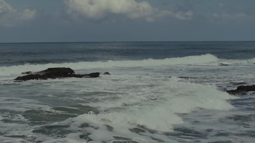 Strong waves crash against rocks in the open sea