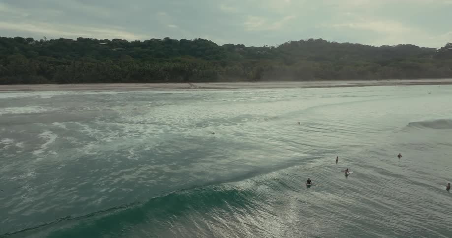 People paddle against waves in the ocean under a clear sky