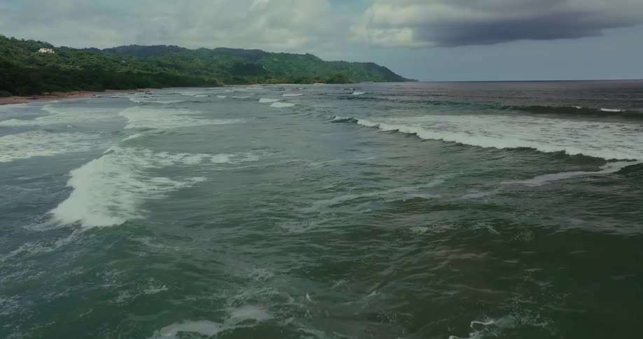 The waves head towards the green shore