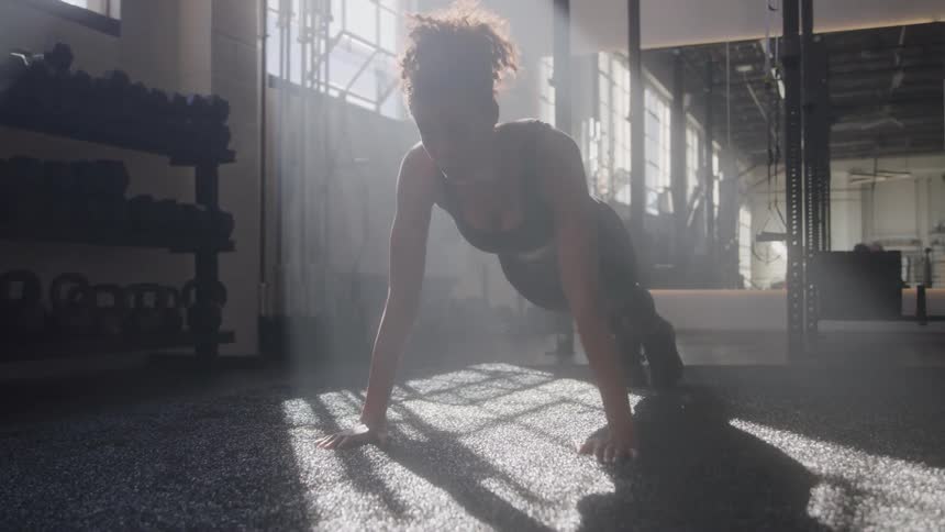 Female performing pushups on carpeted floor at the gym