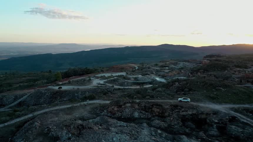 Winding trails on rocky terrain at sunset with mountains in the background