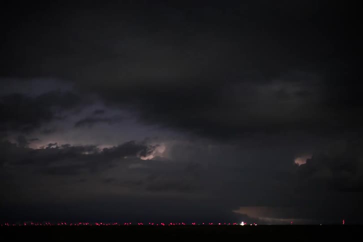Lightning exploding inside dense storm clouds passing each other at night