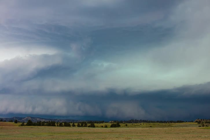 Storm clouds roll over flat grass while lightning flashes