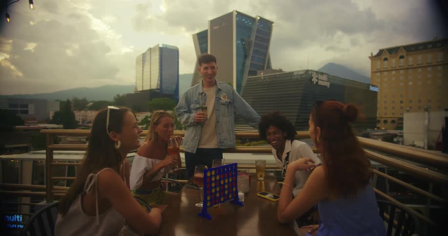 Friends chat and enjoy drinks on a rooftop bar overlooking the city