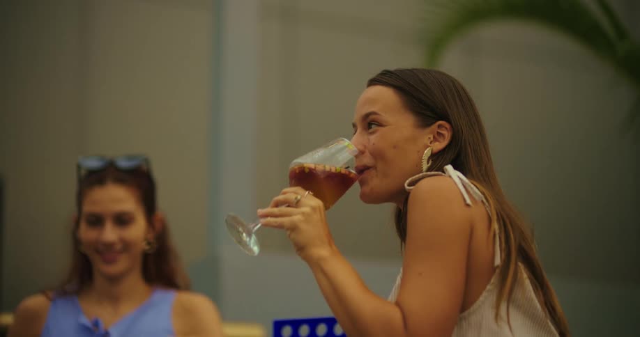 A group of friends laugh and relax together at a table with drinks