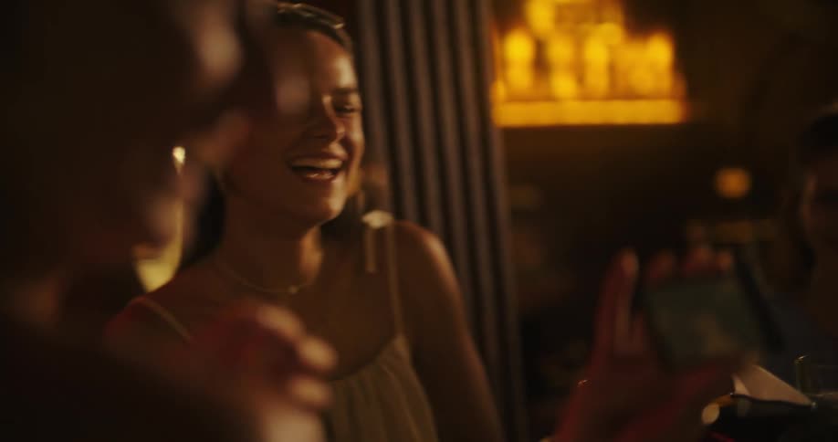 Person holding a cellphone while talking and smiling in a yellowlit setting