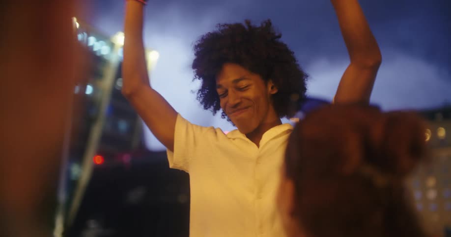 Person dances joyfully with arms raised at a night party outdoors