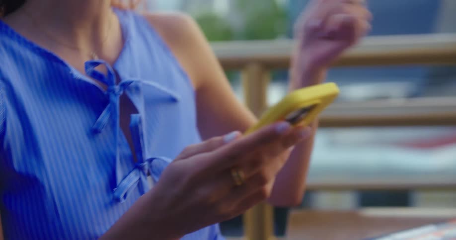 A woman smiles and gestures as she picks up her phone from a table