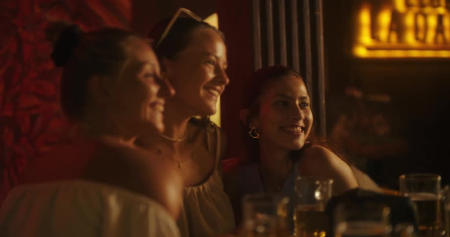 The video shows a group of friends sitting together at a table in a bar or pub they are enjoying a night out laughing and clinking glasses of beer