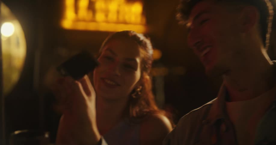A group of friends is gathered at a dimly lit bar enjoying drinks and each others company while engaged in lively conversation