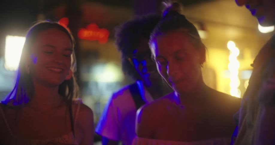 Small group of young people smiling indoors at a bar taking a selfie using a smartphone