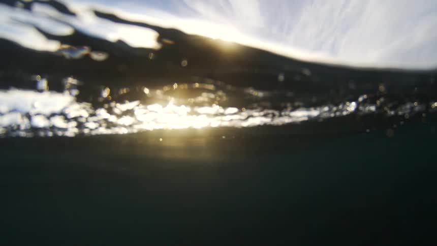 Sun sets over ocean waves seen from the water surface