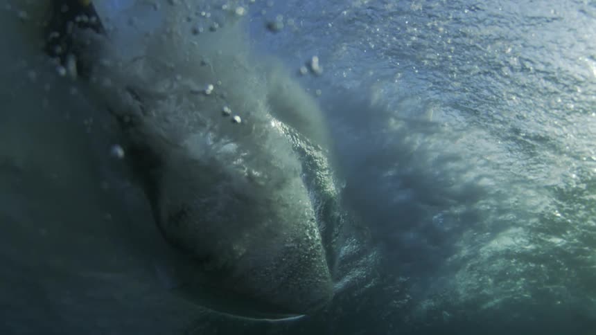 The wave shoots foam underwater when it crashes