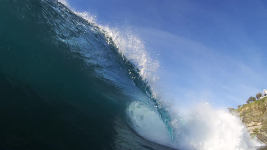 A large ocean wave builds up and curls over before crashing down