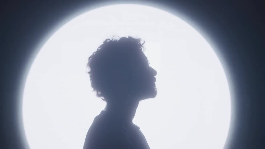 Silhouette of a person in front of illuminated square panels in a dark setting