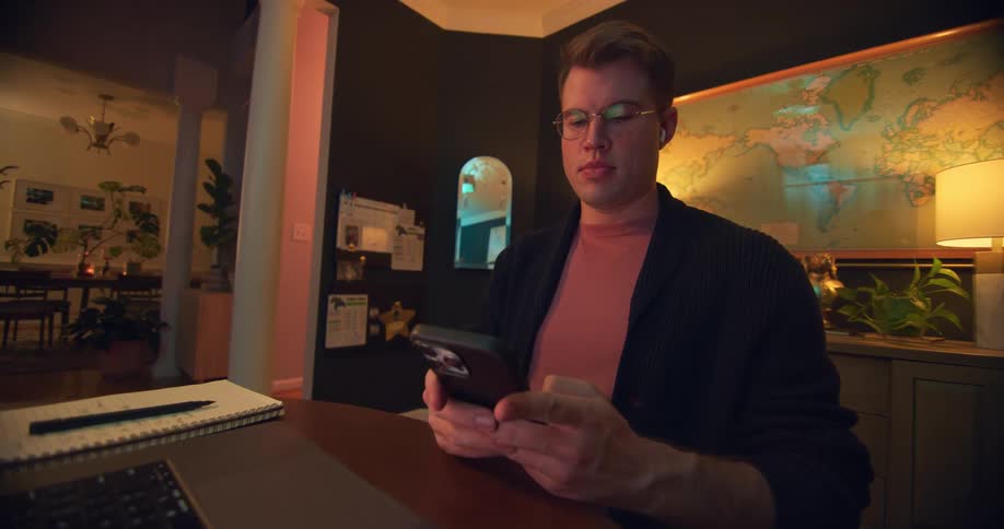Man sitting at a table at night and typing on a smartphone