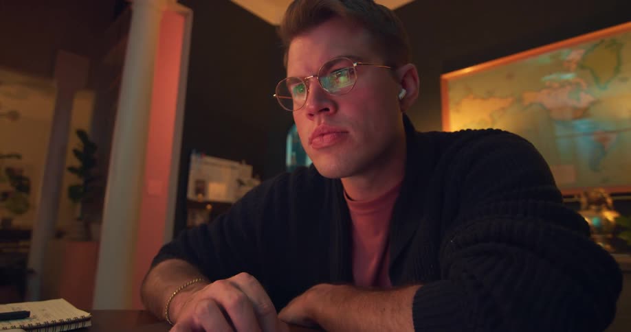 Close up of a young man using a laptop computer while sitting at a table indoors