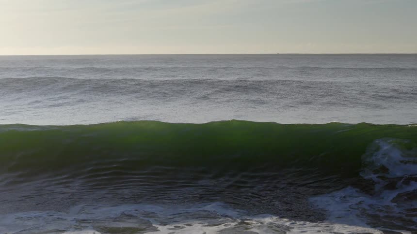 Waves breaking in the middle of the ocean with the horizon on the background