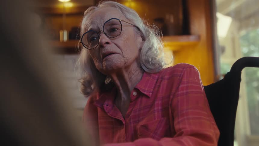 Elderly woman smiling with a joyful expression while talking in a cozy setting