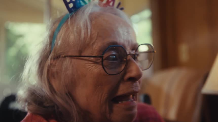 Two elderly people in a room sitting and hugging each other