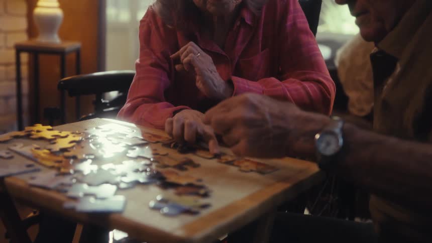 Elderly couple assembling a puzzle together at a table