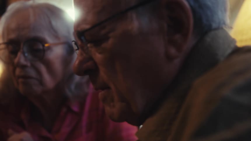 Close up of an elderly man and woman arranging a jigsaw puzzle together at a table indoors during daytime