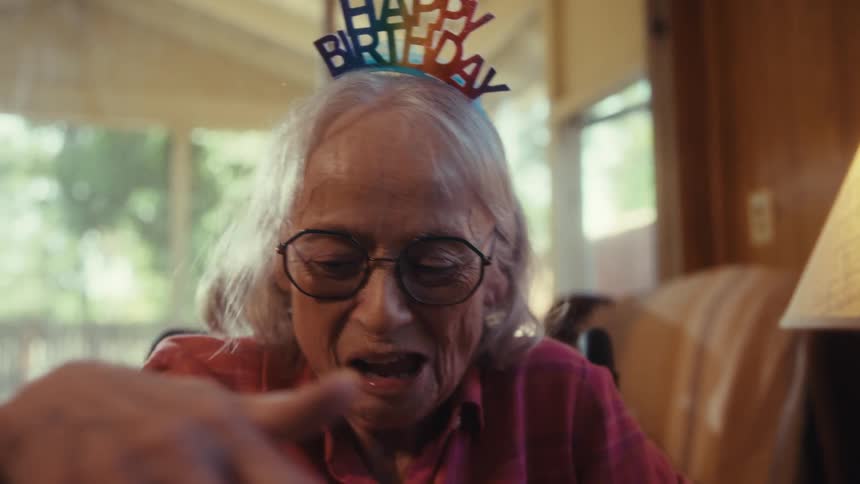 An elderly couple laughs and hugs while celebrating together