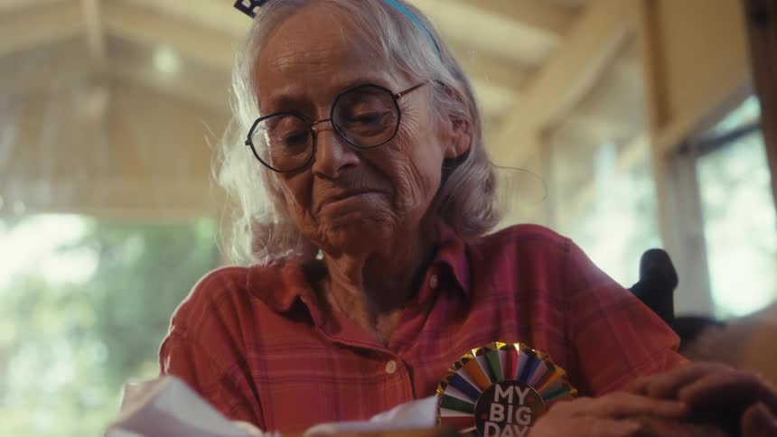 Elderly couple smiles exchanging affection beside wrapped gift