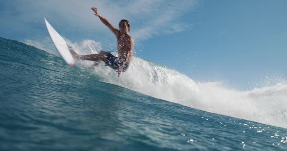 Surfer rides a big wave and water splashes as he turns