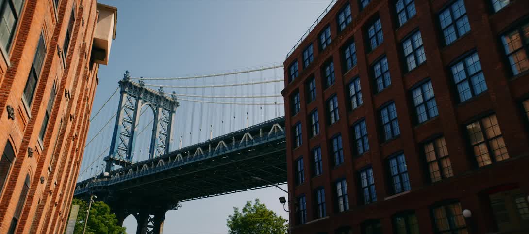 Suspension bridge seen between red brick buildings